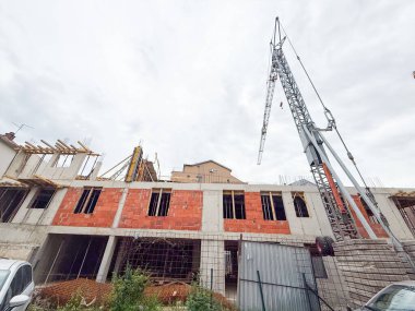 Kırmızı tuğlaları ve beton iskeleti olan kısmen inşa edilmiş bir bina. Yapısal elementleri ve devam eden çalışmaları gösteren kentsel gelişim sahnesi.