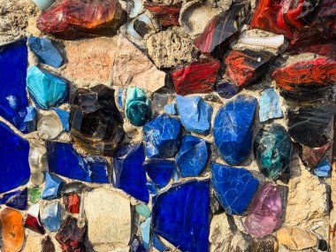 Renkli cam ve taş parçaları soyut bir duvar mozaiği oluşturur. Kentsel yaratıcılık ve mimari ayrıntı