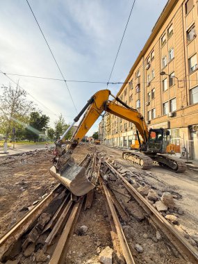 Kazıcı gün batımında eski tramvay raylarını kaldırıyor. Kentsel ulaşım yenileniyor
