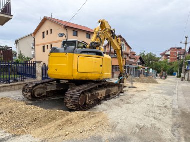 Bir yerleşim bölgesinde sokak kazısı. İnşaat makineleri ve çakıl yığınları devam eden kentsel altyapı bakımını gösteriyor