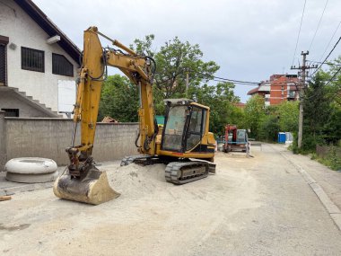 Kazıcı yol çalışması sırasında bir yerleşim yerine park etmiş. Kenar mahallelerde altyapı onarımı