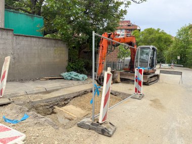 Bloke caddedeki hendeğin yanında küçük bir kazıcı var. Konut hizmetleri çalışmaları devam ediyor