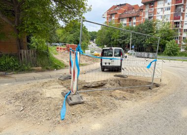 Yol kenarındaki kazı alanı bariyerler ve park etmiş bir servis minibüsüyle korunuyor. Altyapı bakımı devam ediyor