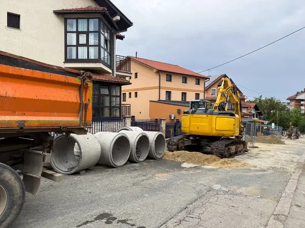 Kazıcı ve beton borular yerleşim yerlerinde. Bir banliyö caddesinde kentsel altyapı onarımı sürüyor