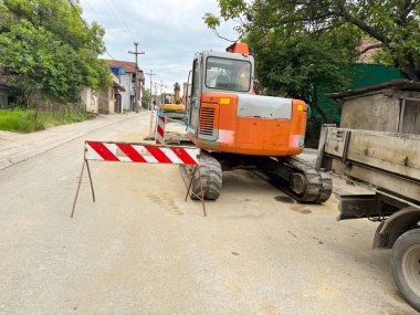Turuncu kazıcı ve inşaat bariyeri yerleşim yerlerini kapatıyor. Kentsel altyapı onarım çalışmaları devam ediyor