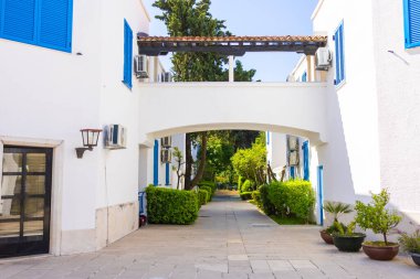 Beyaz binalar arasındaki kemer yolu. Akdeniz tatil köyü, huzurlu bahçe yolu ve kıyı ortamında yaz mimarisi.
