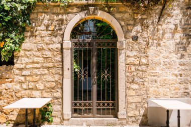 Demir kapı kemerli kapının altındaki taş duvara yerleştirildi. Akdeniz avlusu, klasik mimari ve güneşli açık hava cazibesi..