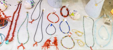 Beyaz yüzeyde sergilenen el yapımı takılar ve mercan aksesuarlar. Sanatçılık, renkli moda ve sahil hediyelik eşya tasarımı.