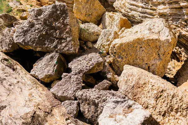 Kırık kireç taşı blokları kayalık yamaçlara saçılmış. Açık havada doğal erozyon, jeoloji ve ham mineral dokusu.