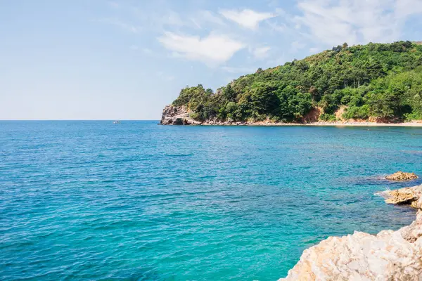 Rocky kıyı şeridi canlı turkuaz denizle buluşuyor. Kıyı manzarası, yaz doğası ve sakin açık hava keşfi.