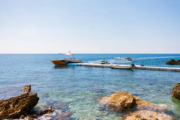 Gemiler açık turkuaz denizde yüzen iskeleye demirlediler. Yaz tatili, su taşımacılığı ve kıyı tatili.