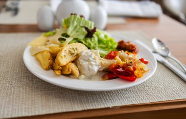 Yemek masasında salata, kızarmış sebze, patates ve peynir tabağı. Sağlıklı öğle yemeği seçeneği, dengeli beslenme ve otel yemeği konsepti