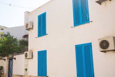 Mavi panjurları, kemerli duvarları ve bahçe manzarası olan rahat bir otel terası. Akdeniz mimarisi, barışçıl geri çekilme ve büyüleyici açık hava oturma alanı.