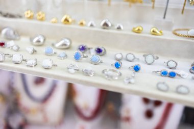 Gümüş ve mücevher yüzükleri bir kuyumcuda sergileniyor. Lüks moda, ince işçilik, ve opal ve safir mücevherlerin güzelliği.