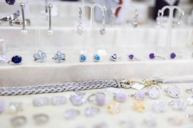 Değerli yüzükler ve bileziklerle güzel bir mücevher sergisi. Lüks aksesuarlar, moda zarafeti ve şık perakende sunumu için ince işçilik.