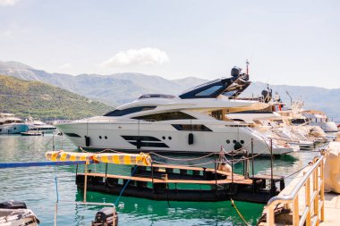 Güneşli bir sahil gününde marinaya yanaşmış lüks bir yat. Yaz seyahati, elit eğlence ve Akdeniz kıyısı turizminin yaşam tarzı.