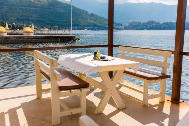 Deniz manzaralı açık bir kafe ve boş hasır sandalyeler. Akdeniz bölgesinde kıyı rahatlığı, yaz turizmi ve deniz kıyısında akşam yemeği..