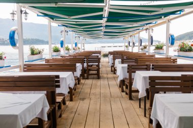 Deniz manzaralı açık bir kafe ve boş hasır sandalyeler. Akdeniz bölgesinde kıyı rahatlığı, yaz turizmi ve deniz kıyısında akşam yemeği..