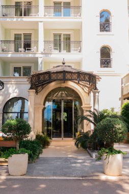 Süslü tepe örtüsü ve manikürlü bitkilerle dolu bir otel girişi. Lüks konukseverlik, mimari detay ve seyahat konaklama tasarımı.