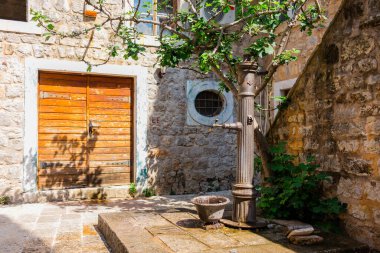 Yapraklı ağacın altındaki eski avlu çeşmesi. Tarihi cazibe, kamu su kaynağı ve Akdeniz atmosferi