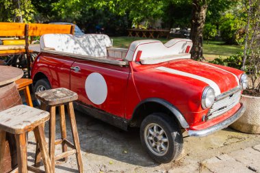 Dönüştürülebilir kırmızı araba açık hava koltuğu olarak yeniden tasarlandı. Klasik otomotiv dekoru, yükseltilmiş tasarım ve tuhaf kafe atmosferi