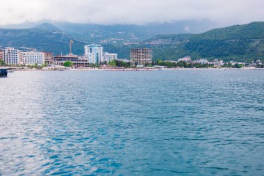 Kıyı kasabasının ufuk çizgisi bulutlu bir yaz gününde denizden görülüyor. Karadağ 'da liman mimarisi, sahil turizmi ve deniz kenarı gelişimi