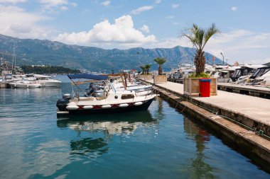 Motorlu tekne dağ arkaplanlı manzaralı bir marinada demirlemiş. Sahil yaşam tarzı, deniz eğlencesi ve deniz kıyısında yaz turizmi.