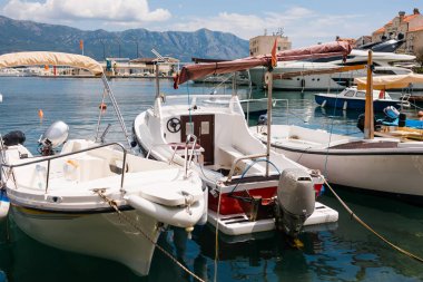 Motorlu tekne dağ arkaplanlı manzaralı bir marinada demirlemiş. Sahil yaşam tarzı, deniz eğlencesi ve deniz kıyısında yaz turizmi.
