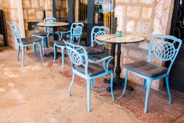 Güneşli verandada yastıklı mavi teras sandalyeleri. Açık hava zarafeti, Akdeniz eğlencesi ve yaz konukseverliği tasarımı.