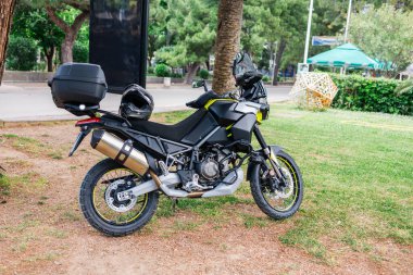 Yeşil yol kenarına park etmiş bir motosiklet. Açık hava, seyahat özgürlüğü ve motosiklet turu ekipmanları.