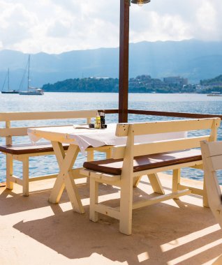 Deniz manzaralı açık bir kafe ve boş hasır sandalyeler. Akdeniz bölgesinde kıyı rahatlığı, yaz turizmi ve deniz kıyısında akşam yemeği..