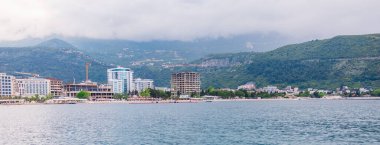 Kıyı kasabasının ufuk çizgisi bulutlu bir yaz gününde denizden görülüyor. Karadağ 'da liman mimarisi, sahil turizmi ve deniz kenarı gelişimi
