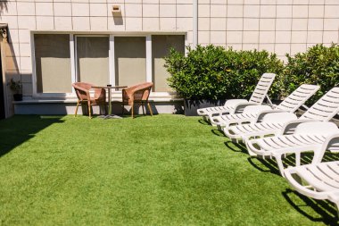 Güneşli yatakları ve hasır sandalyeleri olan bir çatı katı. Açık hava rahatlama, yaz tatili ve güneşli bir otel avlusunda günlük şehir konukseverliği.