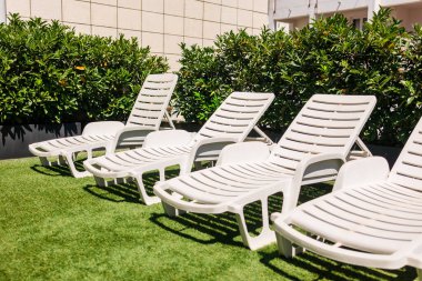 Suni çim çatıdaki beyaz şezlonglar. Kentsel güneşlenme, yaz tatili ve yerleşim yerlerinde boş zaman geçirme.