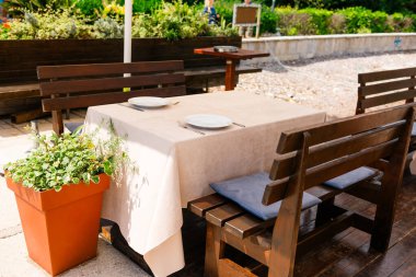 İki kişilik açık restoran masası. Yaz yemeği, doğal ortam ve güneşli bir bahçe ortamında sıradan bir zarafet.