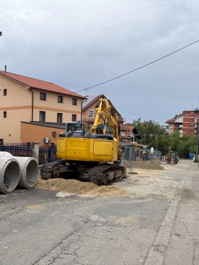 İnşaat sırasında yerleşim yerindeki bir sokakta kazıcı. Şehir altyapısı, karayolu bakımı ve bir banliyö bölgesinde modern gelişim
