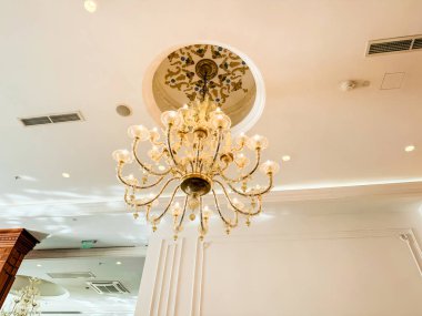 Süslü bir tavandan sarkan kristal süslemeleri olan altın bir avize. Otelin iç ve yemek salonu tasarımında zarafet, lüks, atmosfer ve mimari stil
