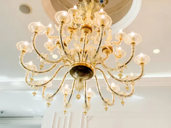 Süslü bir tavandan sarkan kristal süslemeleri olan altın bir avize. Otelin iç ve yemek salonu tasarımında zarafet, lüks, atmosfer ve mimari stil