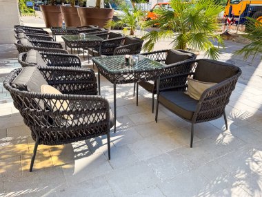 Dokuma sandalyeleri, masaları ve minderleri oturma alanına yerleştirilmiş açık teras. Otel kafe ve sosyal ortamda misafirperverlik, rahatlık, rahatlık ve yaşam tarzı