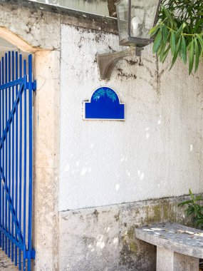 Mavi metal bir kapı ve dış cephesinde fener olan dekoratif duvar işareti. Dış çevre ve sokak görünümünde mimari, kontrast, detay ve kentsel tasarım