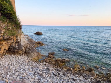 Karadağ 'da gün batımında dalgalar ve ufuklarla kayalık kıyı şeridi. Seyahat, rahatlama, doğa ve deniz manzarası boyunca keşif.