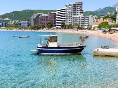 Arka planda modern binalar olan bir balıkçı teknesi rıhtıma yanaştı. Şehir hayatı, denizcilik gelenekleri ve sahilde yaz tatili.