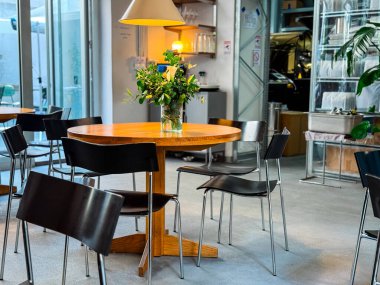 Kafenin içinde ahşap masalar ve duvarında cam raflar var. Kentsel yaşam tarzı, konukseverlik ve sosyal kültür