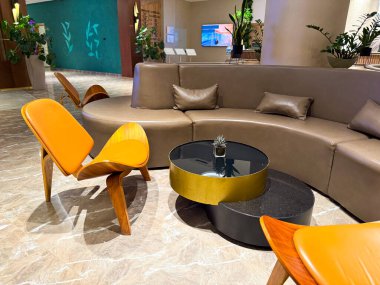 Yuvarlak kanepesi, modern sandalyeleri ve mermer kaplamalı kahve masası olan şık bir otel lobisi. Sosyal alanlar için rahatlama, konfor ve çağdaş konukseverlik tasarımı