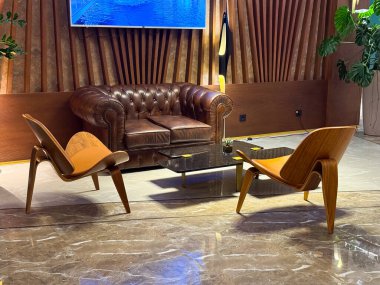Deri koltuklu, tahta sandalyeli ve mermer döşemeli zarif bir otel odası. Retro, konukseverliği, konukseverliği ve misafirperver atmosferi vurgulayan oturma düzeninden esinlendi