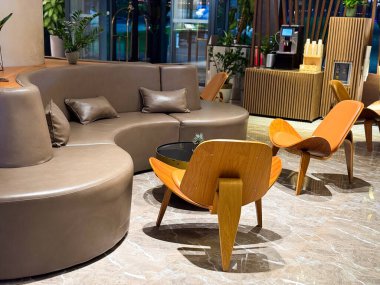 Eğri kanepesi ve tahta sandalyeleri olan modern bir salon. Rahat, konfor ve konukseverlik tasarımı şık otel iç mekanlarında