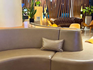 Yastıklı kıvrımlı kanepe ve otel lobisinde kapalı bitkiler. Lüks ortamlarda konukseverlik iç tasarım, rahatlama ve modern konfor
