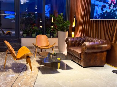 Deri koltuklu, tahta sandalyeli ve mermer döşemeli zarif bir otel odası. Retro, konukseverliği, konukseverliği ve misafirperver atmosferi vurgulayan oturma düzeninden esinlendi