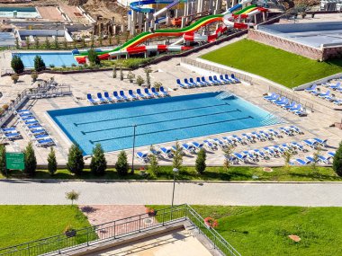 Açık yüzme havuzu, güvertenin etrafına dizilmiş mavi şezlonglar bir tatil köyü. Turizm, boş zaman ve eğlence, tatil yaşam tarzını, refahı ve modern konukseverliği simgeliyor.