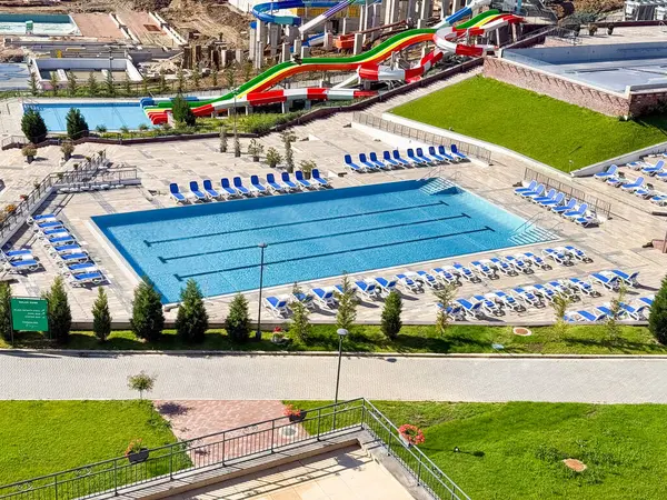 Açık yüzme havuzu, güvertenin etrafına dizilmiş mavi şezlonglar bir tatil köyü. Turizm, boş zaman ve eğlence, tatil yaşam tarzını, refahı ve modern konukseverliği simgeliyor.